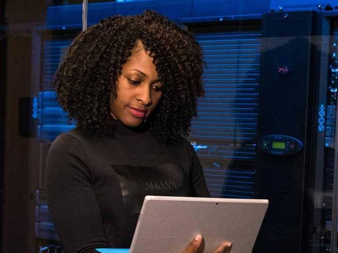 Woman standing up holding laptop focusing